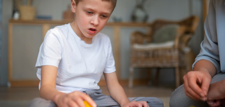 Mum sitting on the floor with son whilst he plays with toy blocks