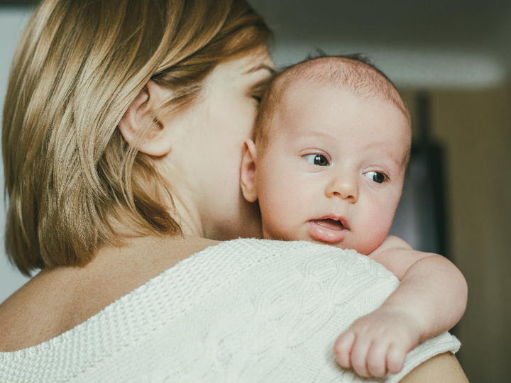 Baby on shoulder of blonde woman