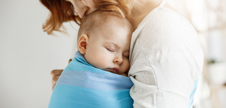 Baby swaddled in sling on the chest of parent