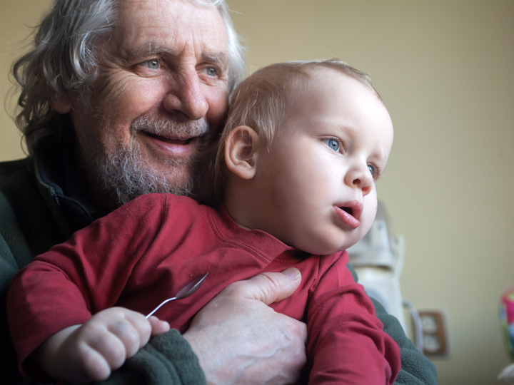 Senior Man Holding on to a Baby Boy at Home