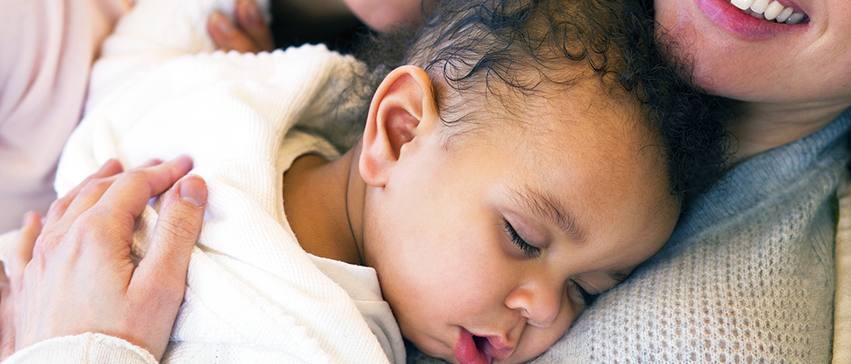 baby sleeping on chest of smiling parent