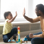 Young child and adult high-fiving whilst sitting on the floor.