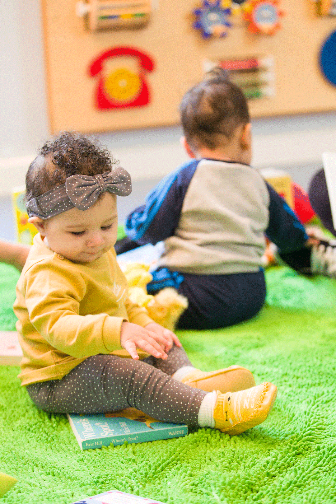 2 children sitting on towel playing with toys