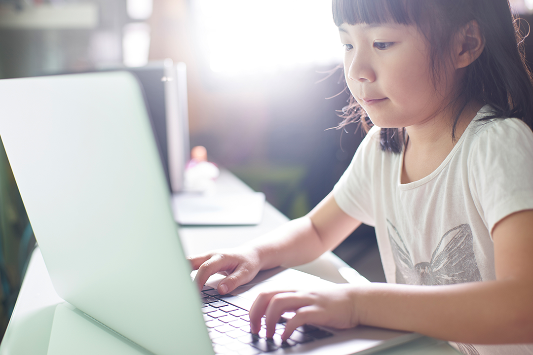 child typing on laptop