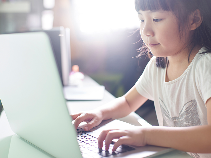 child typing on laptop
