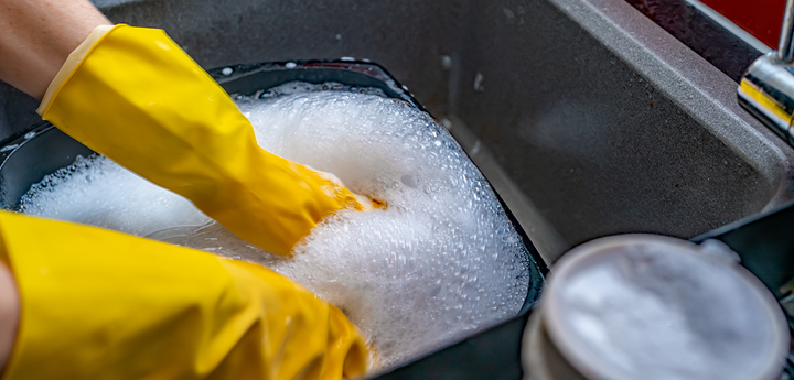 Washing up dishes in a sink with yellow gloves