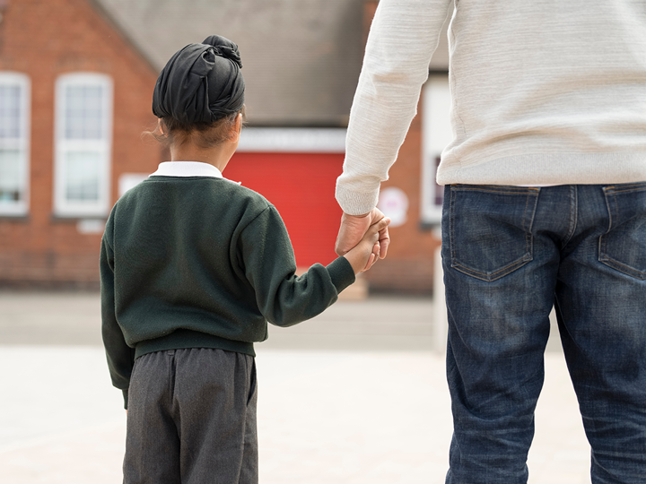 primary school aged Sikh boy holding the hand of an adult