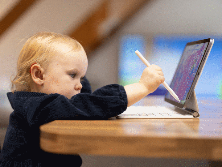 Toddler girl drawing on digital tablet at home