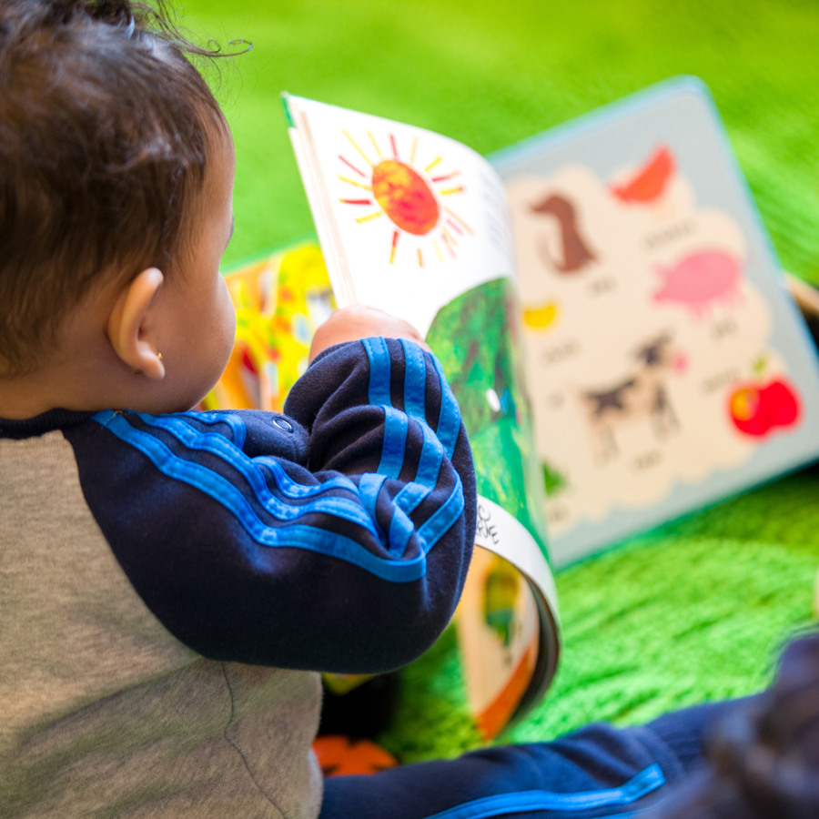 Boy toddler sitting on the floor holding a book and turning the page