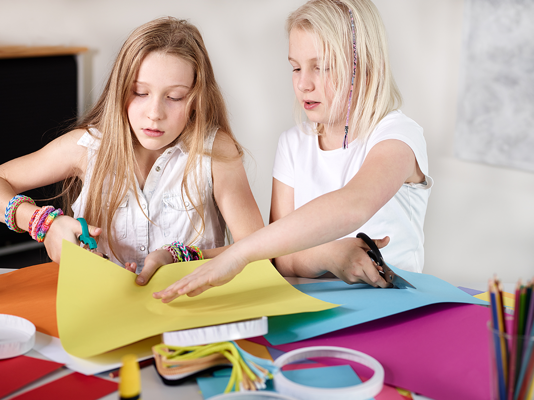 two girls cutting paper together