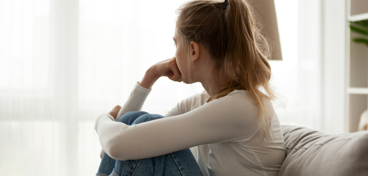 Teenage girl sitting on the sofa looking out of the window