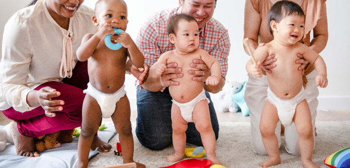 group of adults with standing babies in nappies