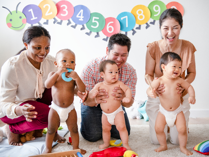 group of adults with standing babies in nappies