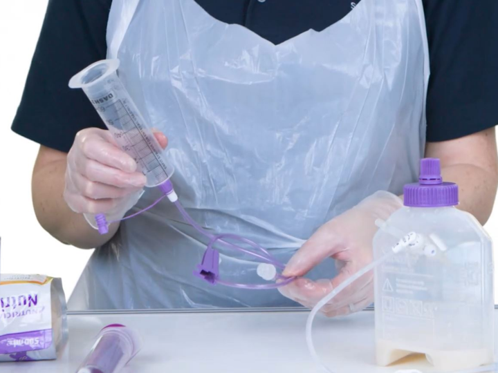 Healthcare worker in scrubs holding feeding equipment