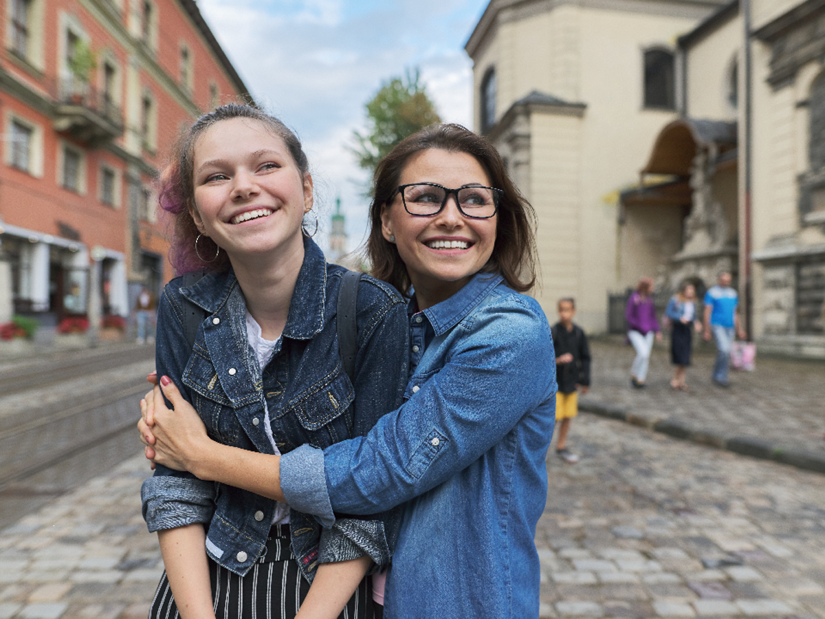 A teenage girl being hugged by an adult