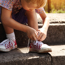 Young boy sitting on steps tying shoelace