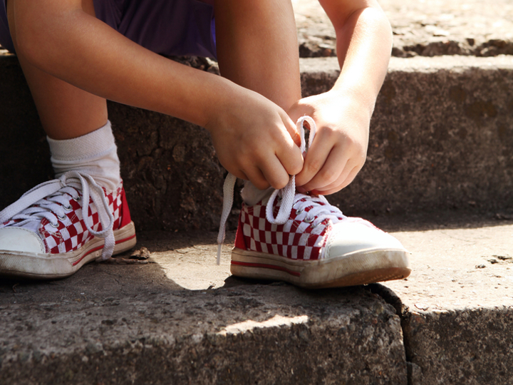 Young boy sitting on steps tying shoelace