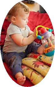 baby sat on carpet floor with legs either side of a stack of pillows and a toy placed on top