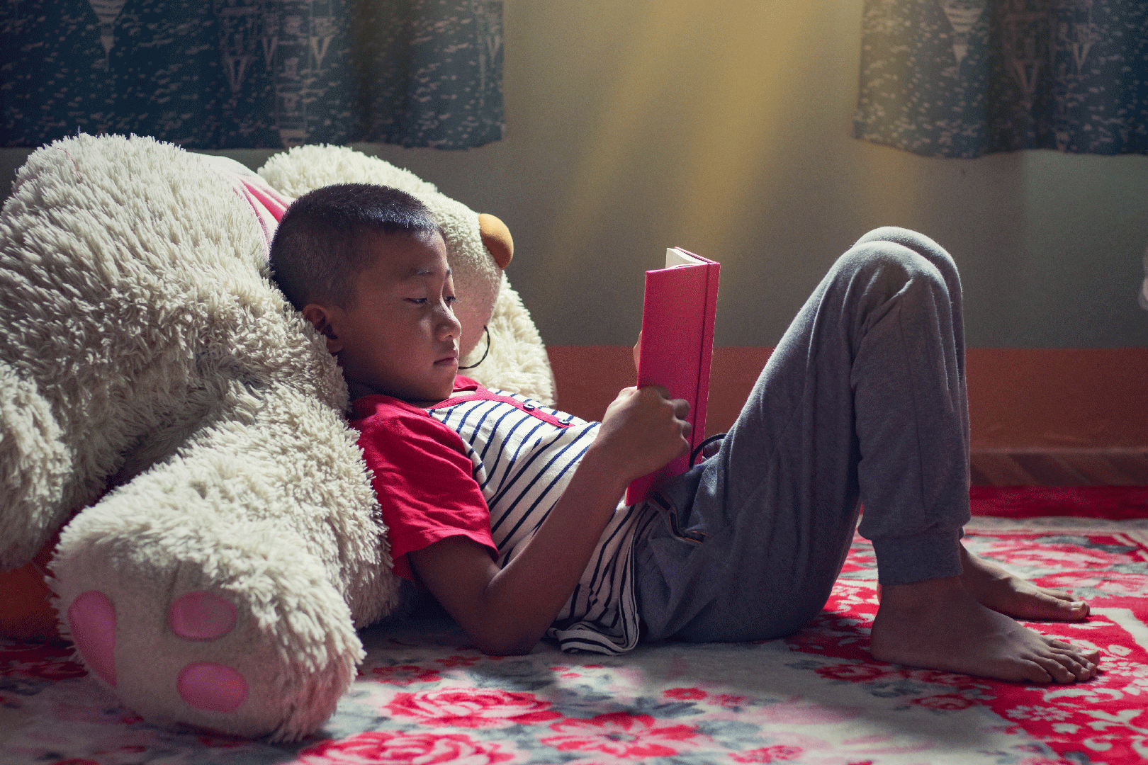 child leaning against teddy bear reading