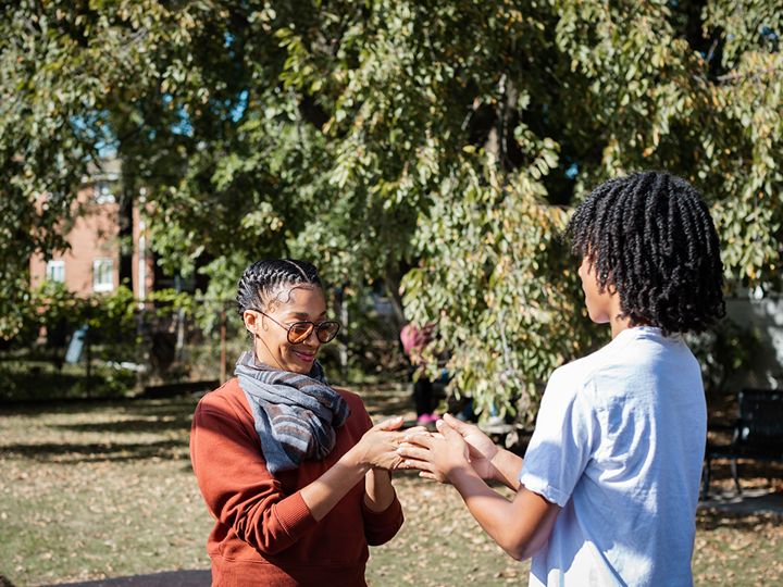 adult woman and teenage boy playing hand slap game outdoors