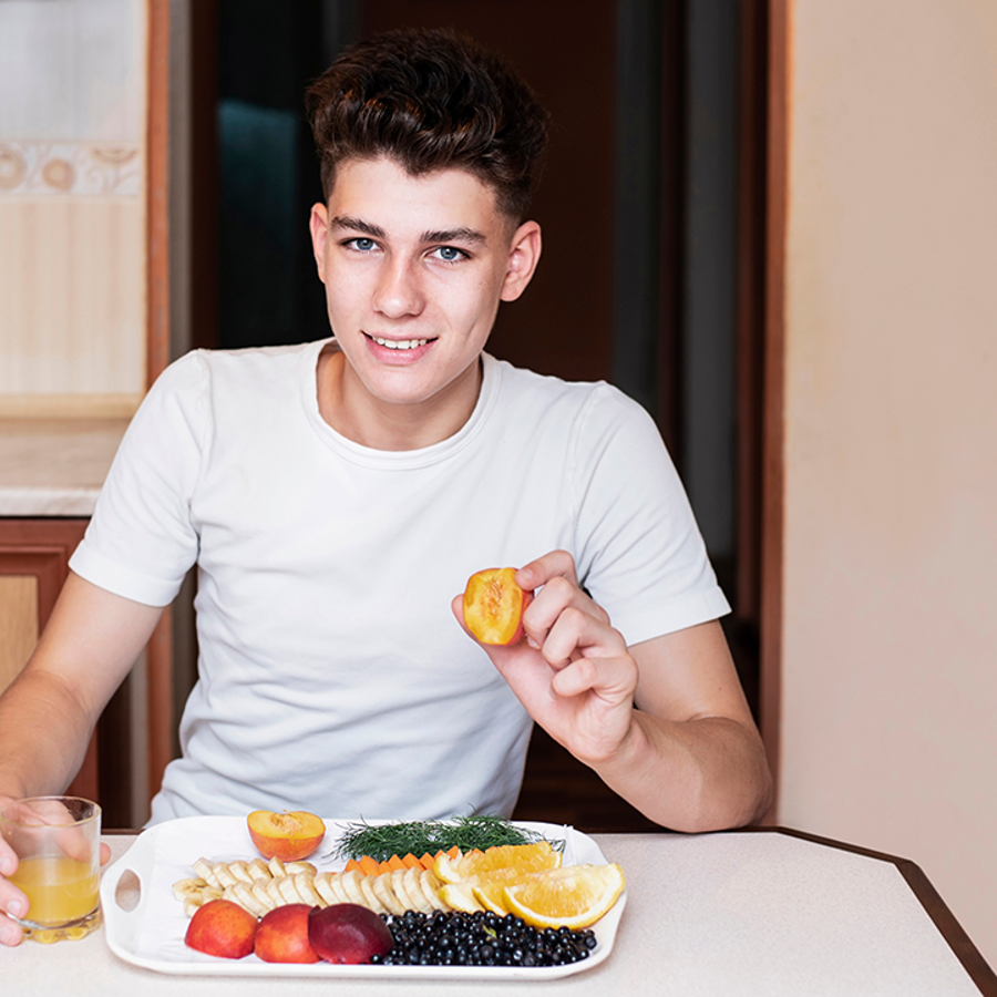 Teenage Boy With A Plate Of Fruit And A Glass Of Orange Juice