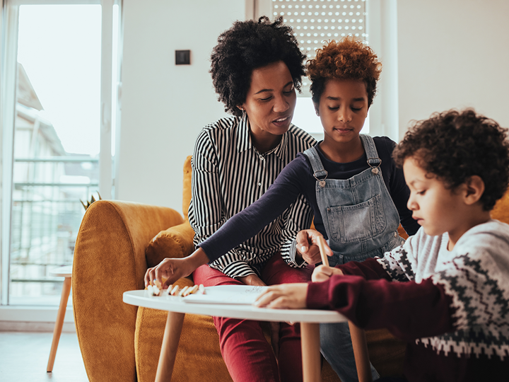 Family writing on paper on small table