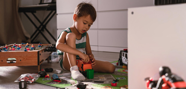 Boy playing in his room with toys scattered around him