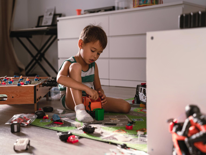 Boy playing in his room with toys scattered around him