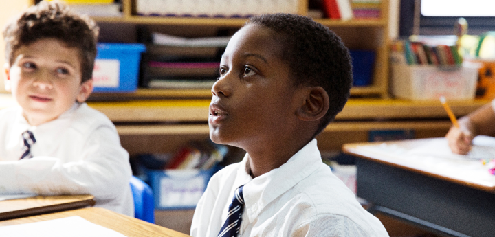 10 year old boy sitting in classroom at desk, looking up