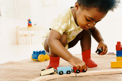 child crouched down playing with wooden train set