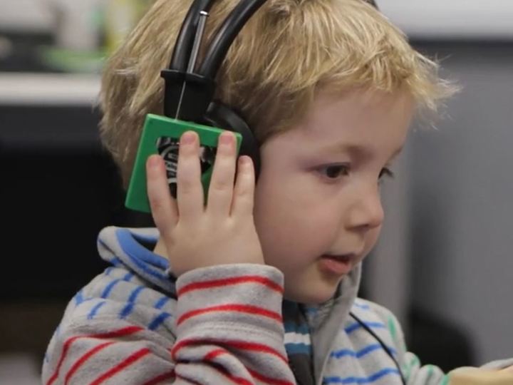 Young boy with headphones on holding a wooden block having a hearing test