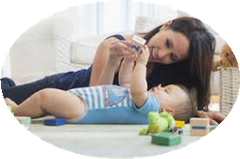 Baby lying on floor with adult playing with toy with arms outstretched