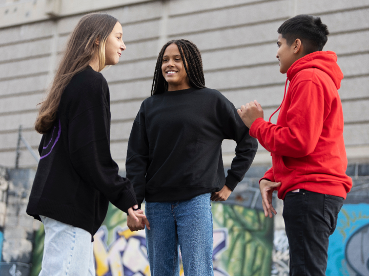 Group of 3 teenagers talking and smiling outside