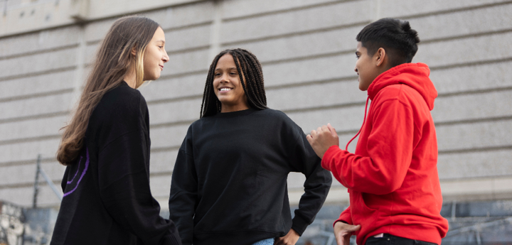 Group of 3 teenagers talking and smiling outside