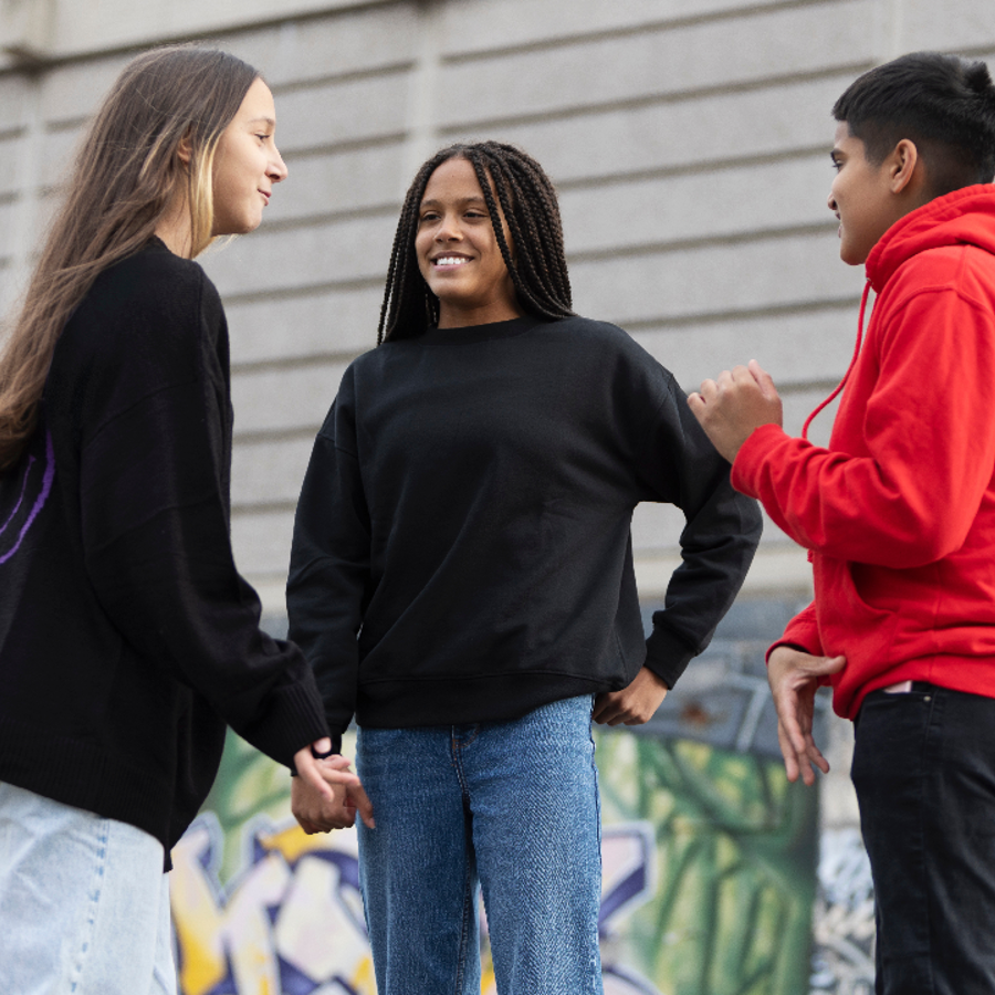 Group of 3 teenagers talking and smiling outside