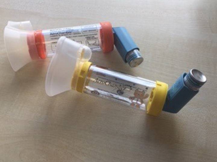 2 aero chambers with inhalers inserted in both of them lying on a table