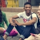 Three teenagers sitting on the ground laughing with each other