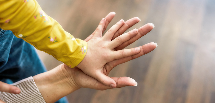child's hand on top of adult hand