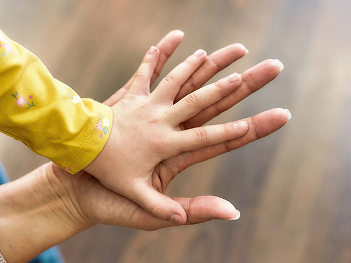 child's hand on top of adult hand