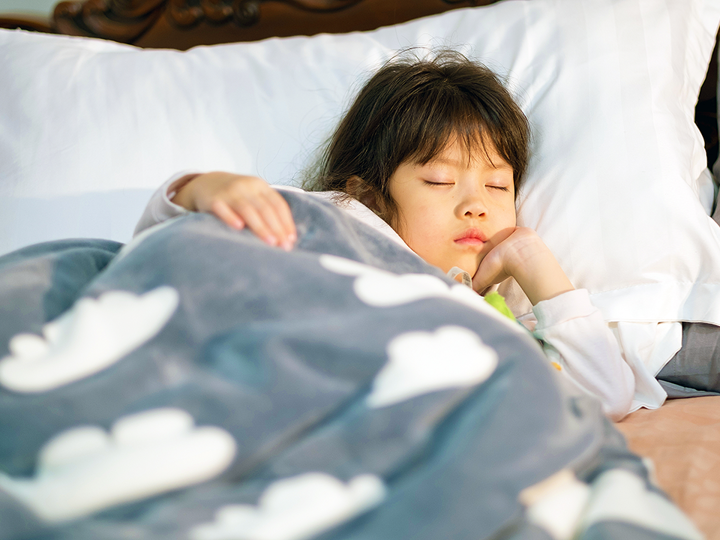 child sleeping in bed with cloud blanket