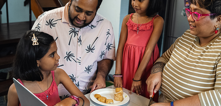 Family Preparing Food Around Laptop