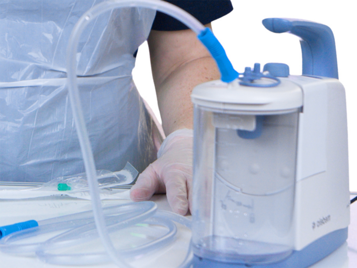 Suctioning equipment with person in scrubs standing behind it