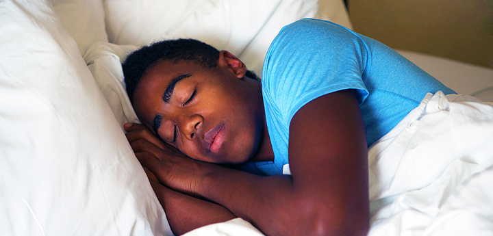 teenage boy with blue t-shirt in bed sleeping