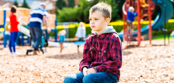 Young boy sitting on a low wall at a park