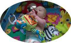 Baby on playmat playing with overhead mobile