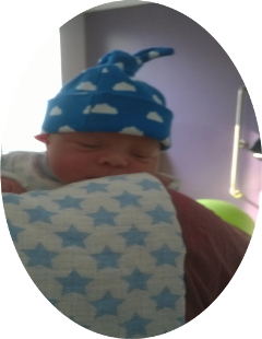Baby with a blue hat resting against adult shoulder