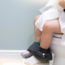 Young child sitting on toilet with feet resting on a step. Holding lots of toilet roll.