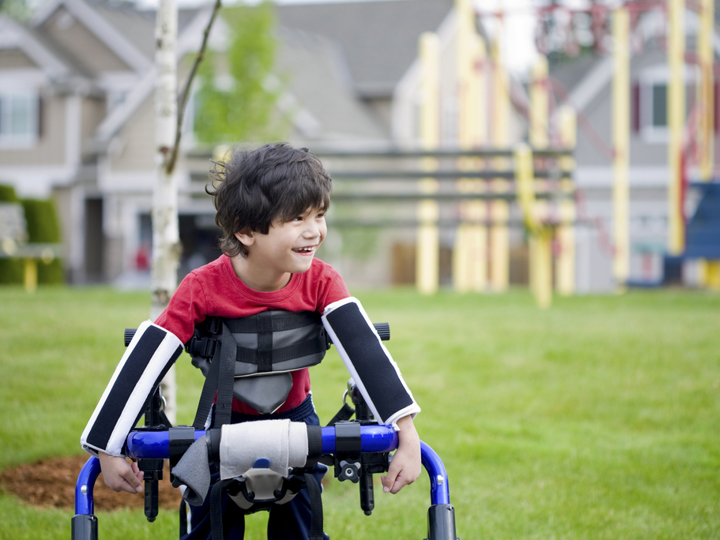 Young boy with walking support outside