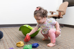 child squatting to pick up bean bags