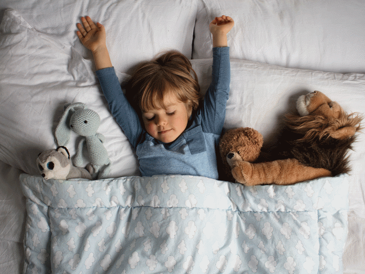 child in bed with stuffed animals